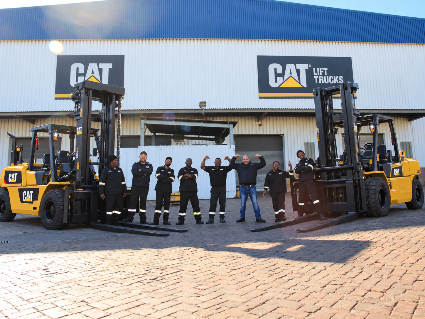 Masslift Africa team standing between two Cat heavy-duty forklifts